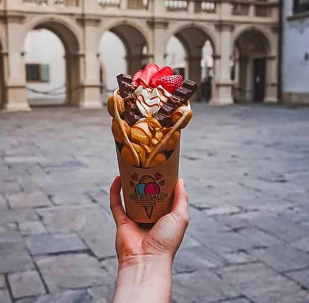 Bubble-Waffel mit Erdbeeren und Schokolade vor einem Arkadenhof in der Grazer Innenstadt – Der Eissalon