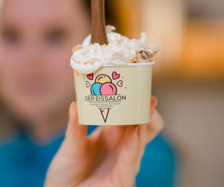 Mitarbeiterin hält einen Eisbecher von Der Eissalon in die Kamera – Der Eissalon Graz